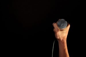 Male hand with microphone isolated on black